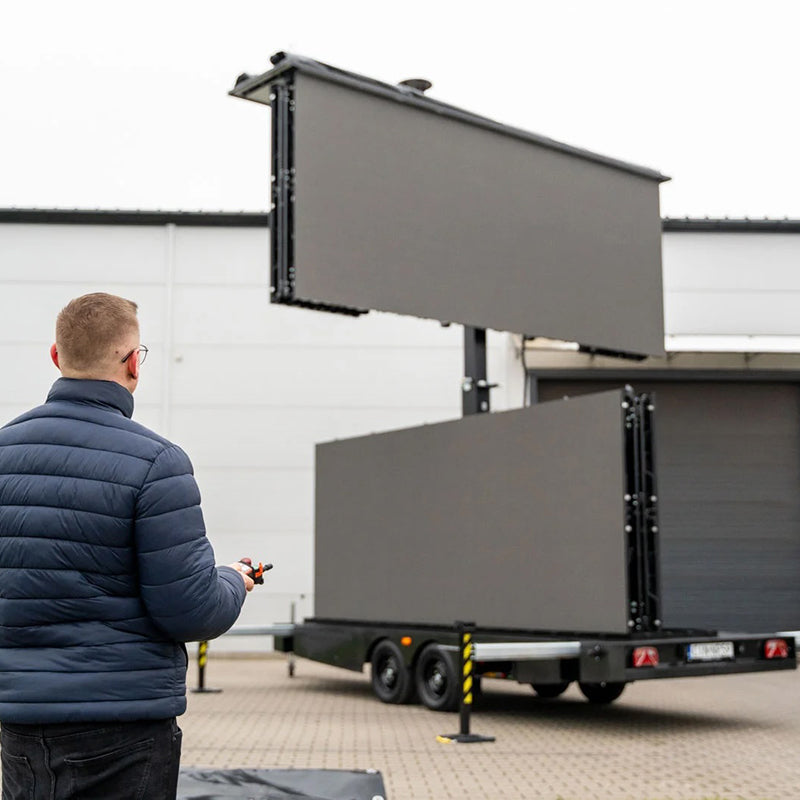 Mann bedient LED Trailer Veranstaltungstechnik mit großen LED-Bildschirmen auf mobilem Anhänger