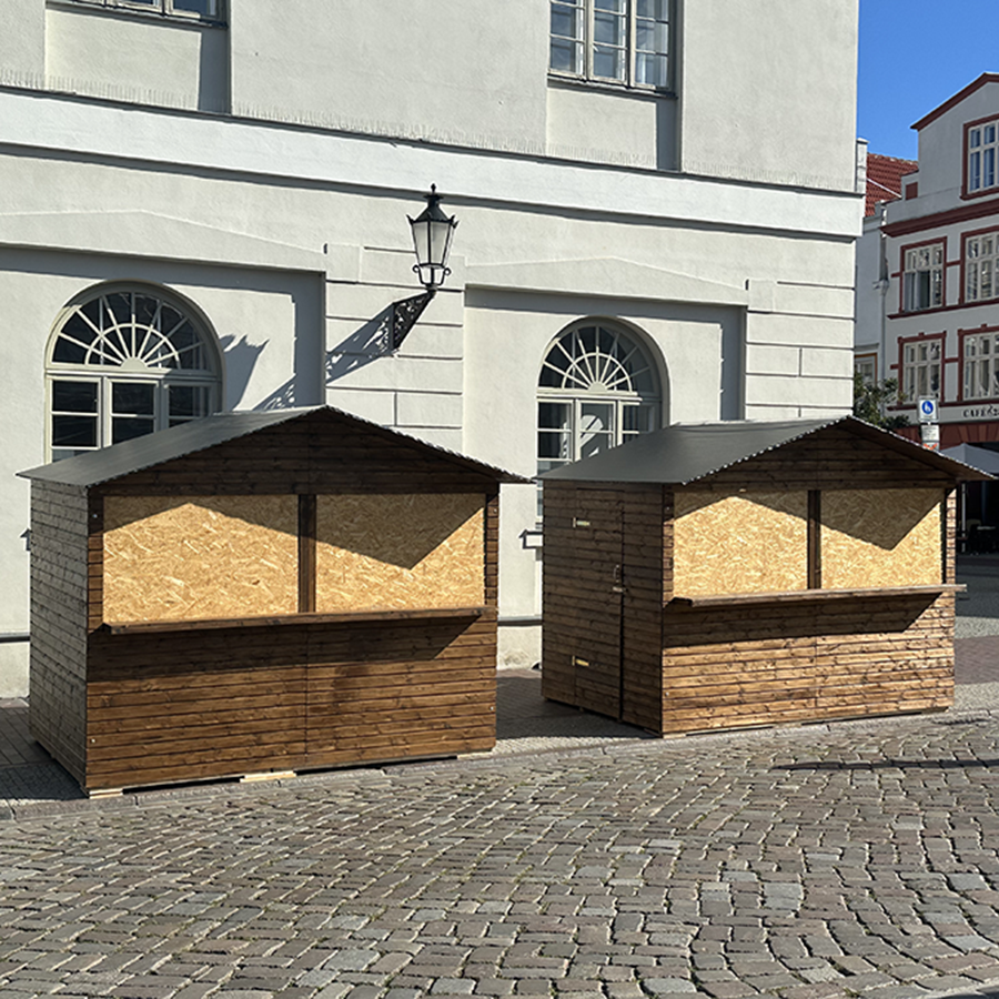 Zwei geschlossene Markthütten aus Holz auf Kopfsteinpflaster vor historischem Gebäude Markthütte mieten