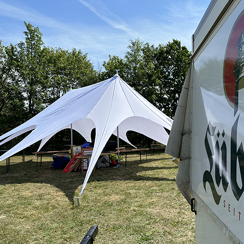 Weißes Sternenzelt aufgebaut auf einer Wiese mit Bäumen im Hintergrund Sternenzelt mieten Wismar